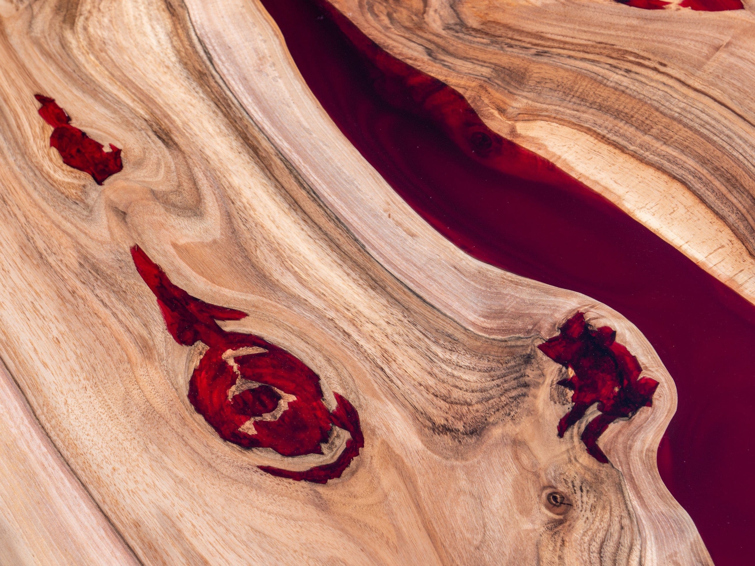 Détail entre noyer massif et résine époxy rouge sur table rivière