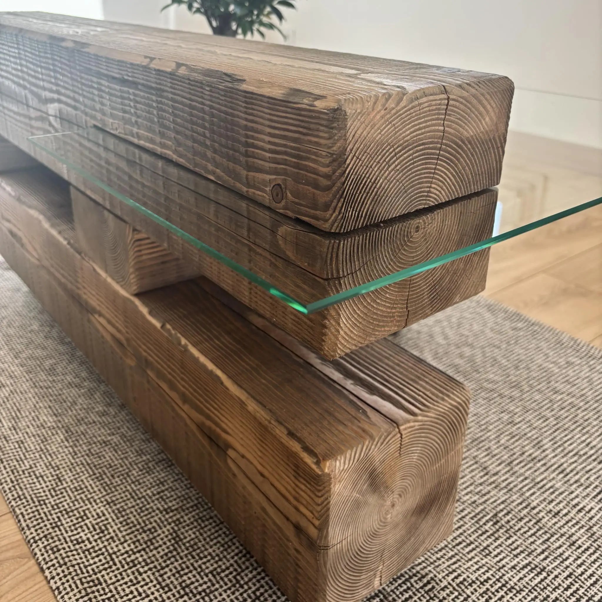 Détail de la table basse Origine montrant l'intégration du plateau en verre dans le bois brossé